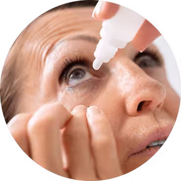Woman holding open her right eye while applying eye drops from a bottle